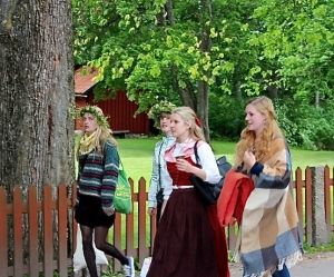 Swedish maidens wearing fancy floral crowns head out to celebrate Midommar.